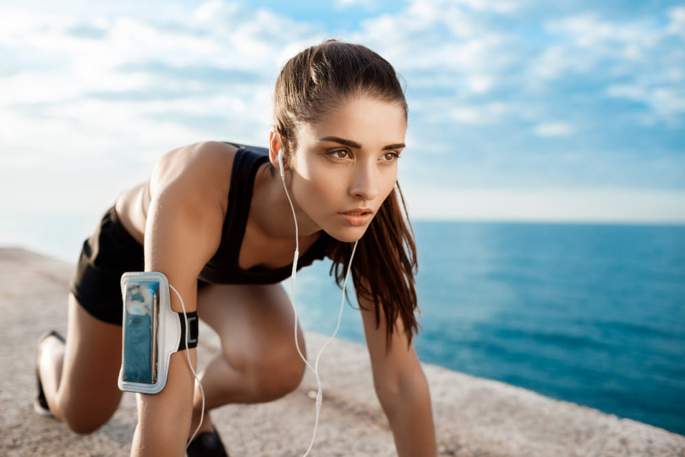 Una runner a punto de empezar a correr con teléfono en el brazo